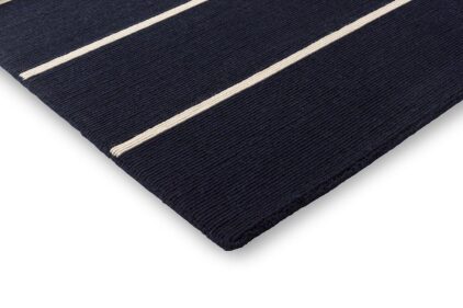 Granatowy dywan w paski do salonu marki Marimekko.