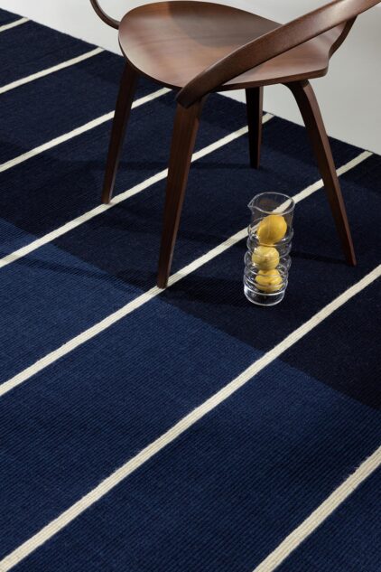 Granatowy dywan w paski do salonu marki Marimekko.