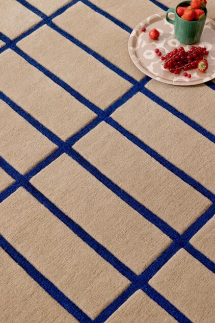 Beżowy dywan geometryczny w niebieską kratkę do salonu marki Marimekko. Efekt 3D.